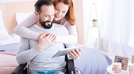 woman hugging man while he looks at tablet