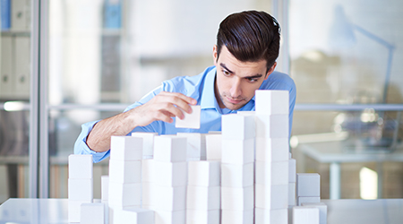 Businessman building towers with blocks 