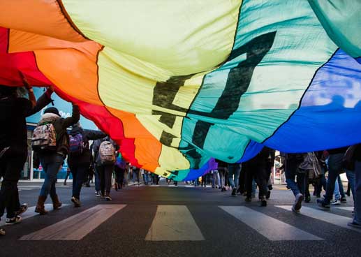 People in a PRIDE parade holding a flag aloft