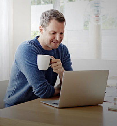Man working on laptop with a coffee mug in his hand