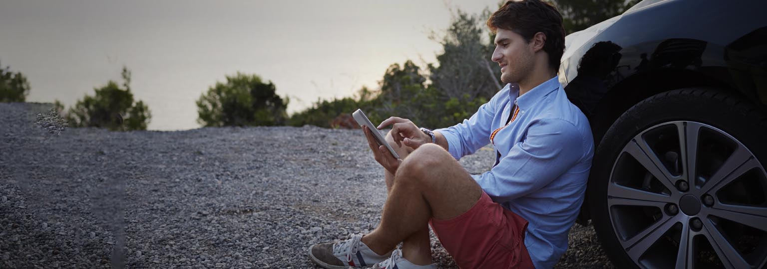 man leaning against car back and working with his mobile