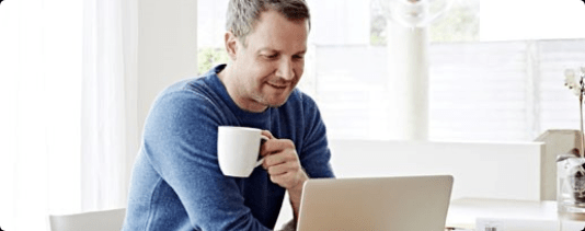 man holding coffee cup and working on laptop
