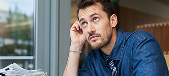man sitting at desk with stack of papers