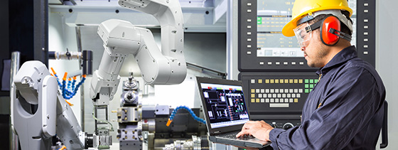 man wearing safety helmet, safety glasses and hearing protection headset and working with robot