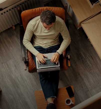 man sitting in chair working at laptop