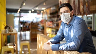 man wearing mask leaning on counter